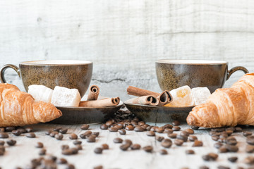 Wall Mural - Cup of coffee with grains, croissant, turkish delight and cinnamon sticks on wooden background