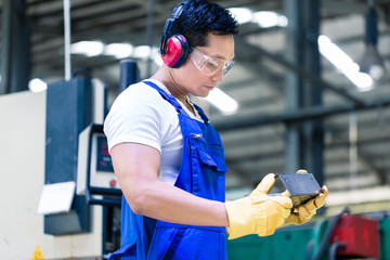 Wall Mural - Worker in industrial factory checking work piece