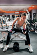 © golubovy - Female athlete training with dumbbells. Young attractive sportswoman pumping up her muscles with dumbbells at gym. professional woman arm wrestler training before competitions