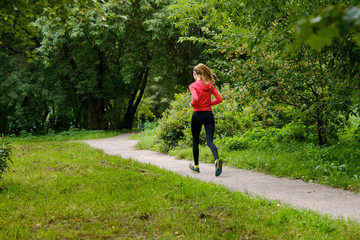 Wall Mural - Young slim woman jogging in a park