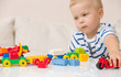 © goodmoments - Close up of child's hands playing with colorful plastic bricks at the table. Toddler having fun and building out of bright constructor bricks. Early learning.  stripe background. Developing toys