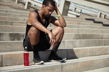 Wall Mural - Sports and fitness. Exhausted African male runner relaxing after