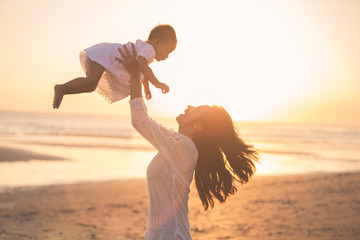 Wall Mural - Portrait of mother and baby in the beach at sunset