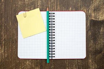 Open notebook with sticky note and pencil