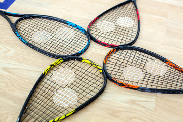 Four tennis rackets are lying on wooden court background - sport, fitness, healthy lifestyle and objects concept