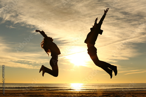 Fotografia Couple or friends jumping on the beach at sunset