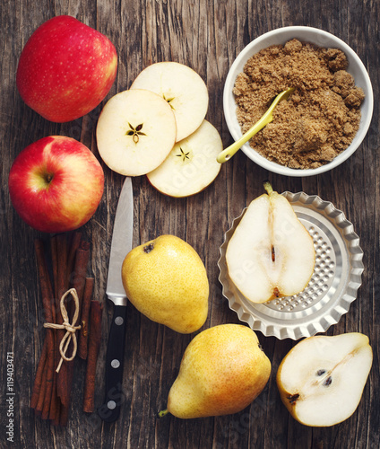 Fotografía Apples, pears, cinnamon sticks and brown sugar on wooden backgro