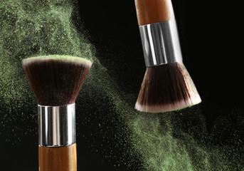 Make-up brush with green powder explosion on black background