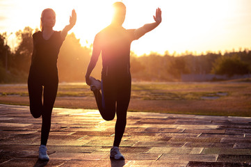 Silhouettes of young adults exercising at sunset