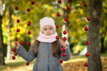 Young girl in autumn park with apple garland