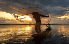 The Siluate  Fisherman Casting A Net Into The Water During On Sunset,Thailand