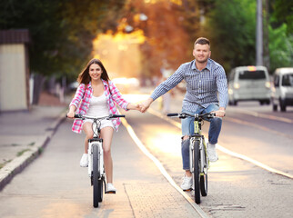 Canvas Print - Young lovely couple riding bicycles on street