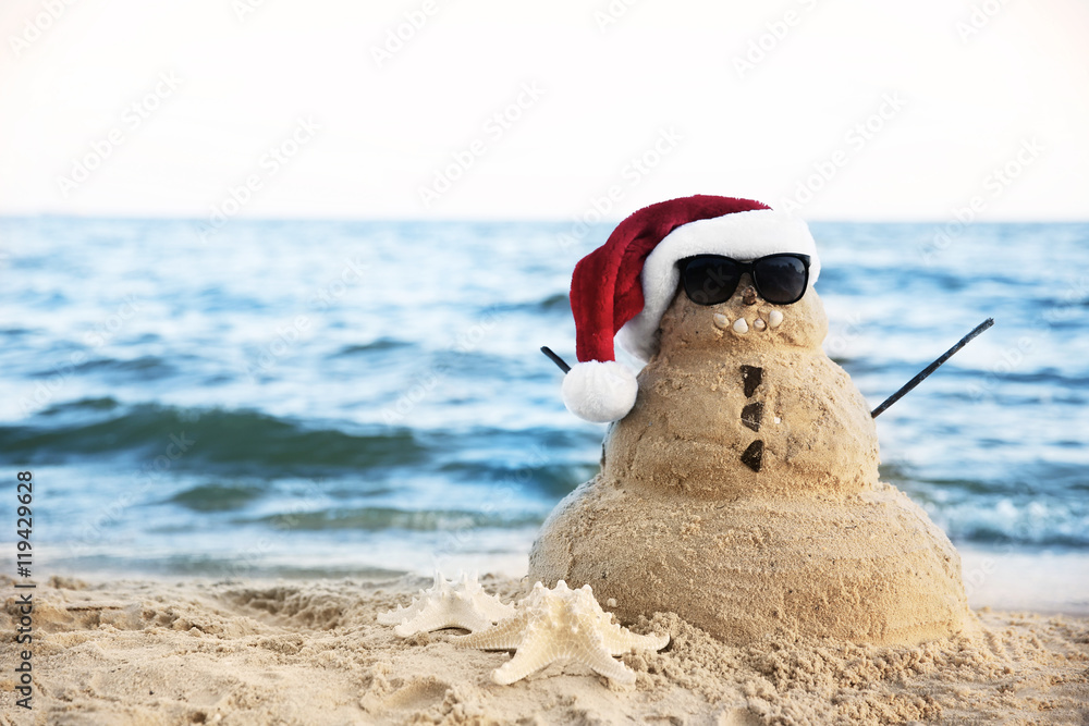 Snowman made of sand on beach. Christmas holiday concept