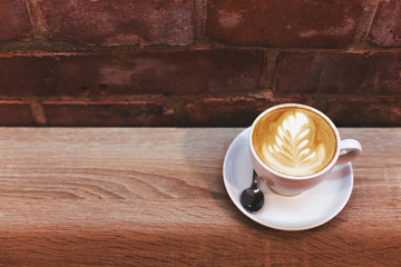 Poster - Cappuccino on the table near brick wall