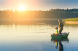Fototapeta Krajobraz - father and son catch fish from a boat at sunset