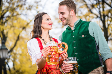 Wall Mural - Mann und Frau in bayrischer Tracht mit Brezeln und Bier in Masskrügen