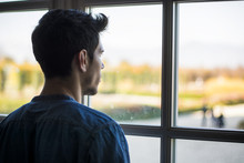 Half Body Shot Of A Thoughtful Handsome Young Man Looking Away Out Of Window, Inside Historic Building In European City