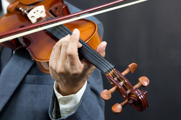 Wall Mural - asian male musician playing violin on dark background