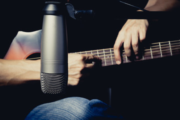 Sticker - male musician playing acoustic guitar behind condenser microphone in recording studio