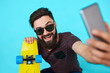 © kegfire - Young hipster with beard in glasses taking selfie and smiling isolated on the blank white background