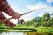 Fisherman holding spinning rod with reel while fishing