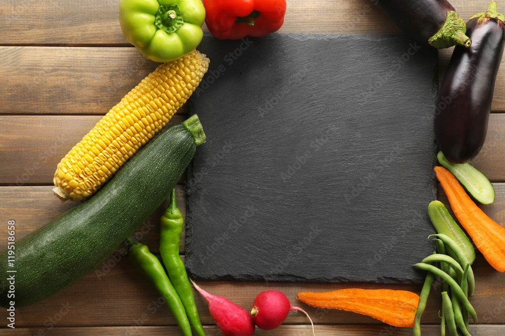 Slate plate and vegetables on wooden background