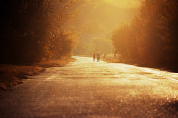 Evening walk. Group of girls walking along road in beautiful evening light. Rural landscape with road. Childhood in village. Backlight