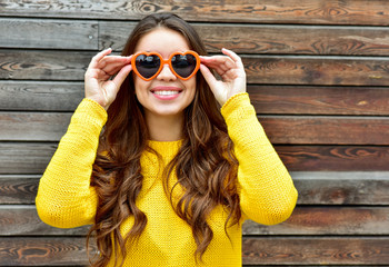 Beautiful smiling brunette woman in sunglasses over wooden backg