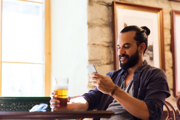 man with smartphone drinking beer at bar or pub