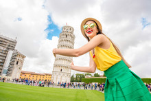 Young Female Traveler Having Fun In Front Of The Famous Leaning Tower In Pisa Old Town In Italy. Happy Vacations In Italy