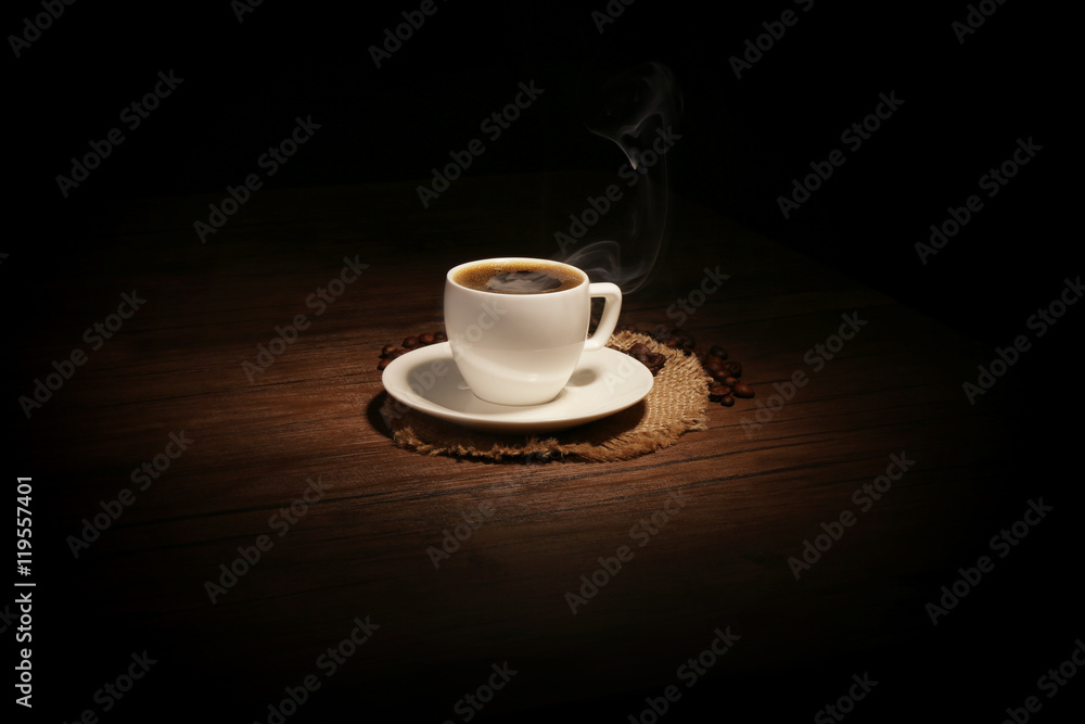 Cup of coffee with beans on wooden background