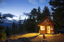 Illuminated Wooden Cabin In Forest At Night