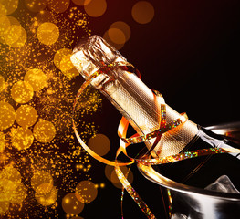 Canvas Print - Bottle of champagne with streamer in bucket on black background. Christmas celebration concept.