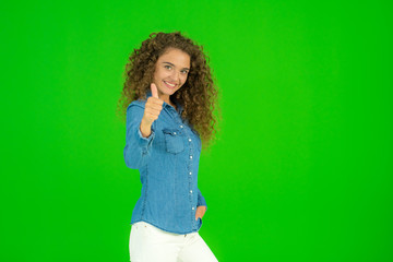 The young woman stand and show thumb up on the green background