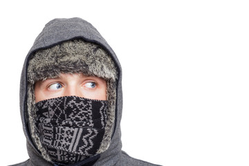 Young man in hat, scarf and hood hiding from the cold weather in the winter