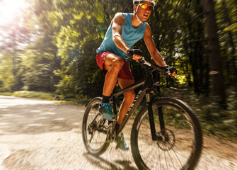 Young man riding a mountain bike on old country road.