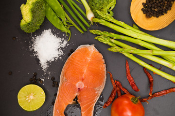 Fresh raw salmon filet with spicy herbs on black plate