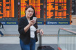 © Song_about_summer - woman with smartphone in international airport checking timetable of the flight.