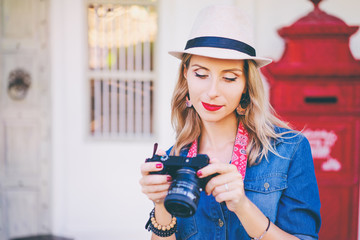 Wall Mural - Hobby and fashion. Young pretty woman in hat holding camera on old town street.