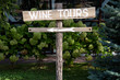 © frimufilms - Wooden wine tour sign with arrow with green shrubs on background