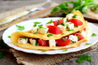 Home stuffed omelet on a plate. Egg omelet stuffed with tomatoes, cheese and green parsley. Vegetarian diet breakfast recipe. Fork, knife, cutting board on wooden background. Closeup