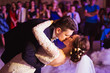 Groom kisses bride while bending over during their first dance