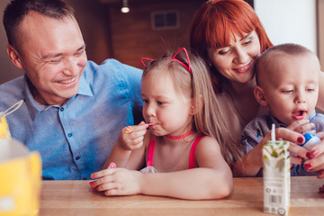 Happy family eating fast food in restaurant all together