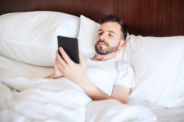 Wall Mural - Man reading an e-book in bed