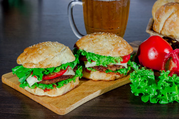 beer and homemade burgers buns with beef patties and fresh salad ingredients