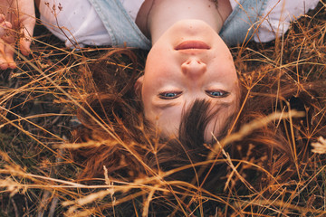 Beauty Young Woman with Brown Hair in Golden Field at Sunset.