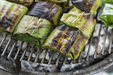 Closeup marinate fish in banana leaf on the grill from the market in Thailand