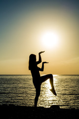 Wall Mural - Silhouette of young girls engaged in sports on the beach