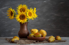 Still Life In A Rustic Style: Bouquet Of Sunflowers In A Ceramic Vase And Pears On A Wooden Table