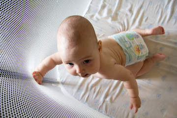 Baby in a diaper in playpen